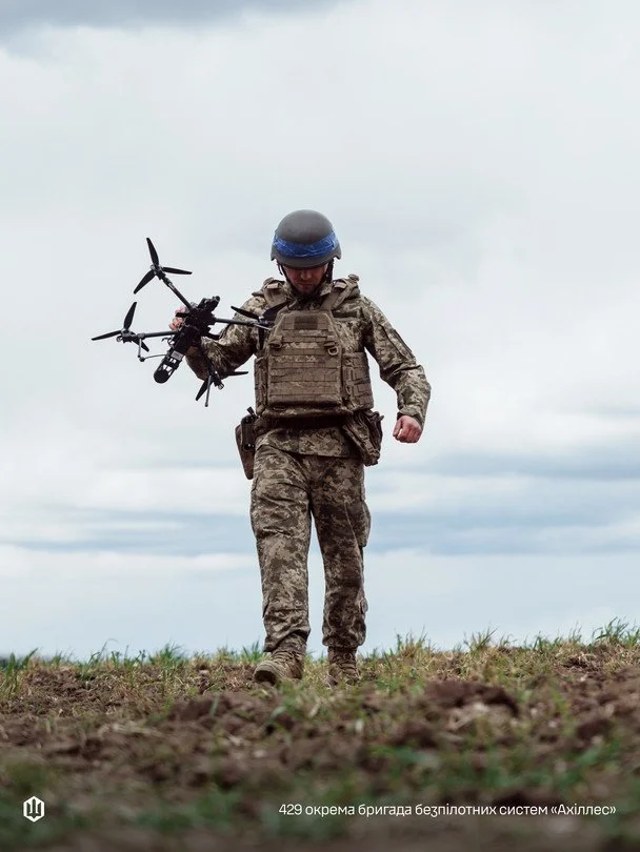 Український військовий із безпілотником на тлі техніки Сил безпілотних систем ЗСУ